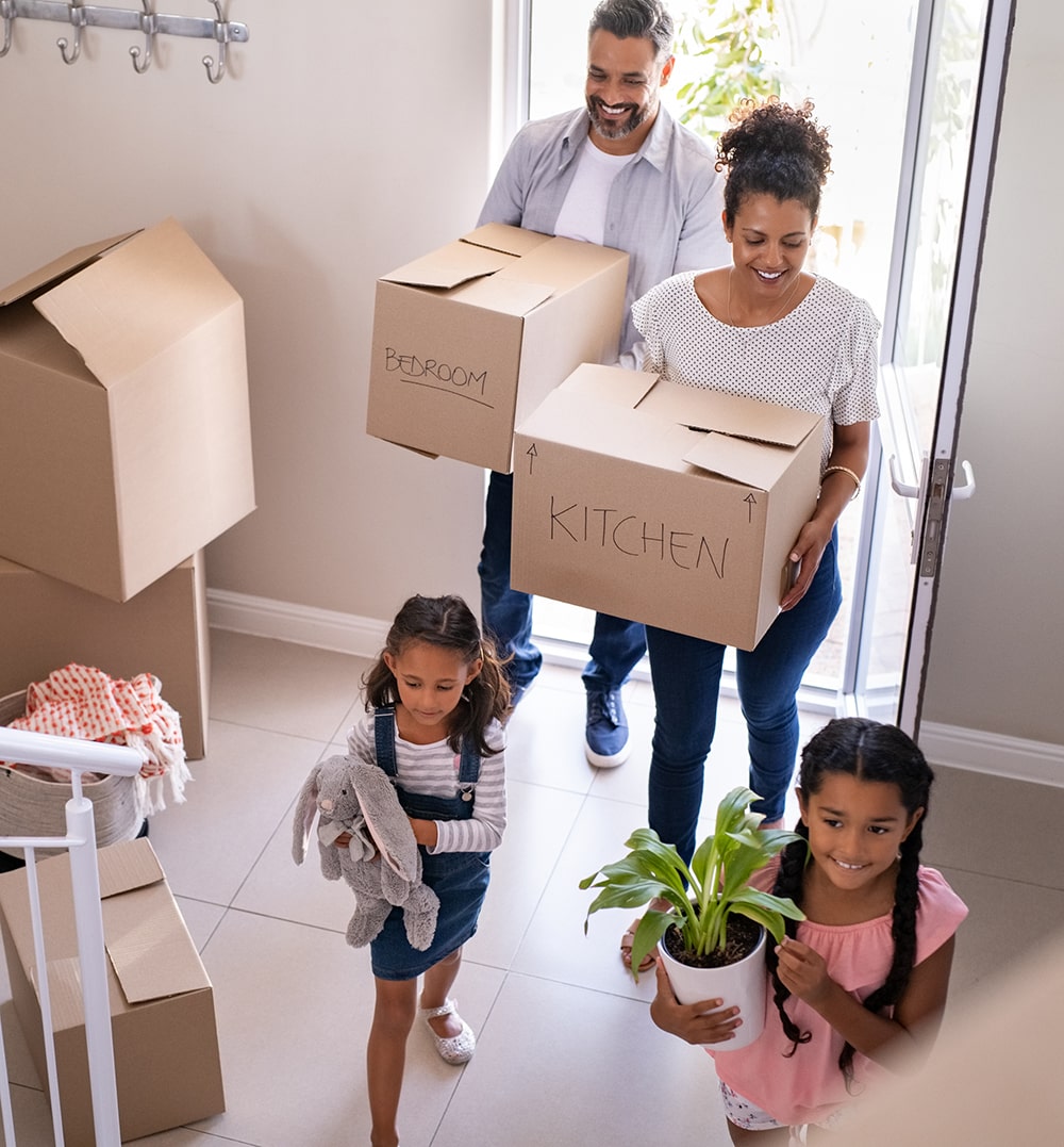 Happy family moving into their new home carrying boxes.