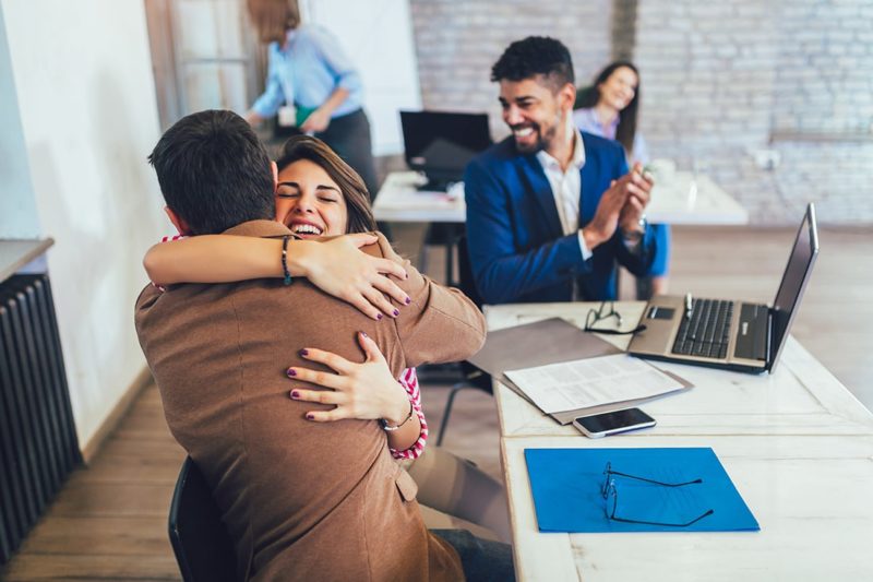 Happy client closing on a home loan, hugging husband